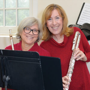Two adult women holding flutes and smiling