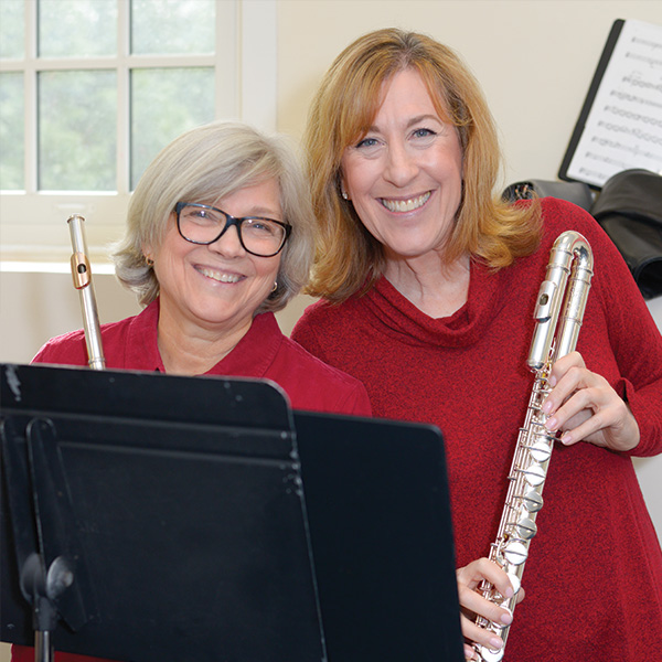 Two adult women holding flutes and smiling