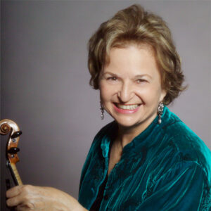 Woman with blonde hair wearing a green shirt holding a violin