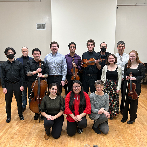 Diverse group of young men and women posing for picture some with musical instruments