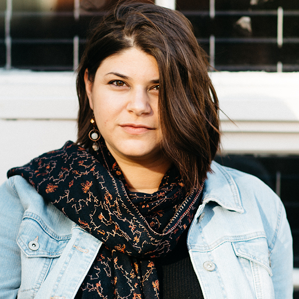 Young woman with brown hair in a jean jacket with a colorful scarf