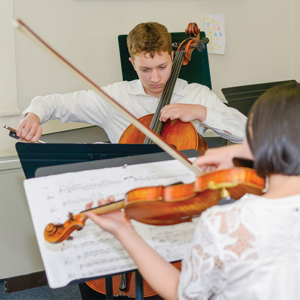 Boy playing cello and girl with back to camera playing violin