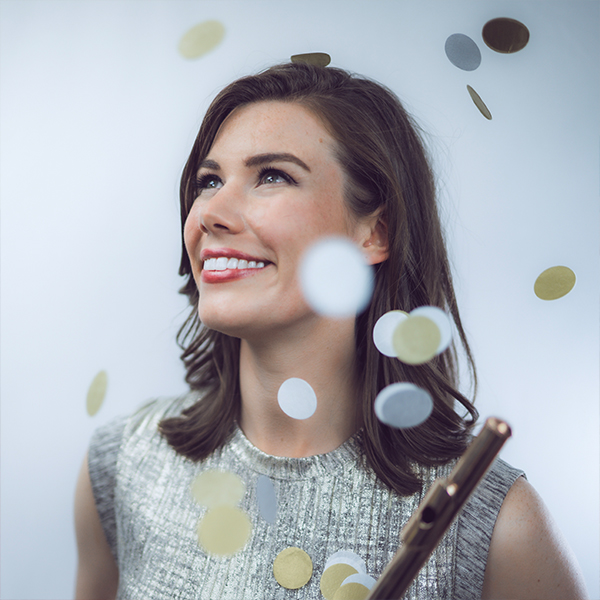 Woman holding a flute smiling with confetti falling from above