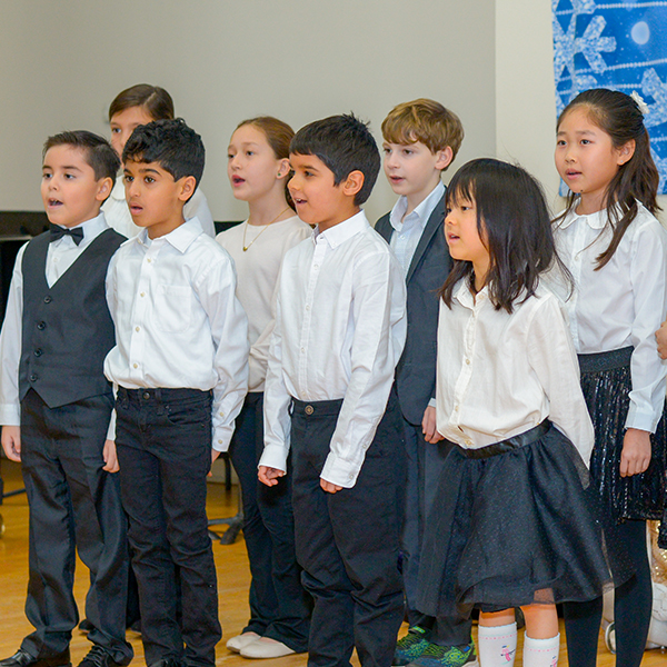 Group of young children singing in a choir dressed in black and white clothes