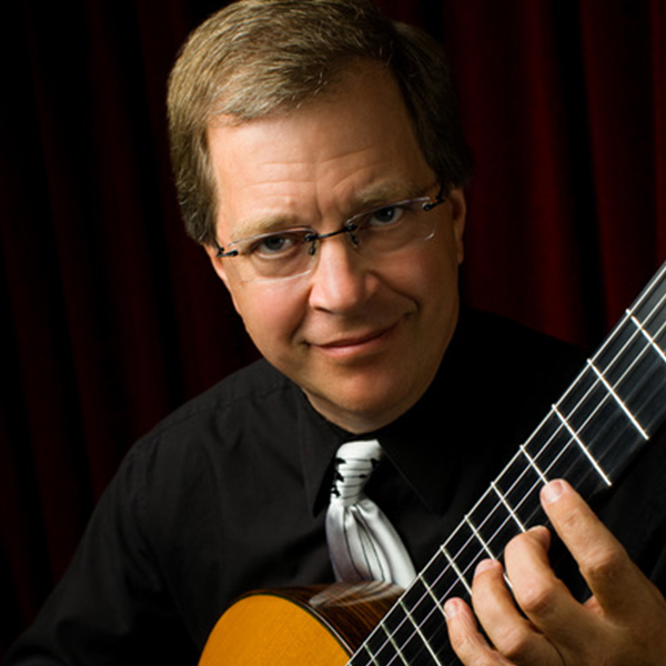 Close up of a man in dark clothing playing the guitar