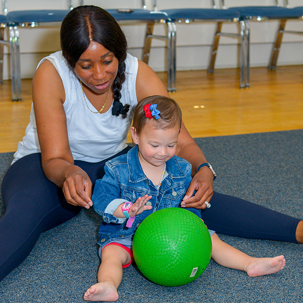 Woman and toddler playing with a green ball