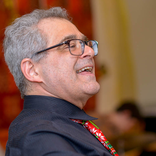 Middle-age man with grey hair and glasses singing