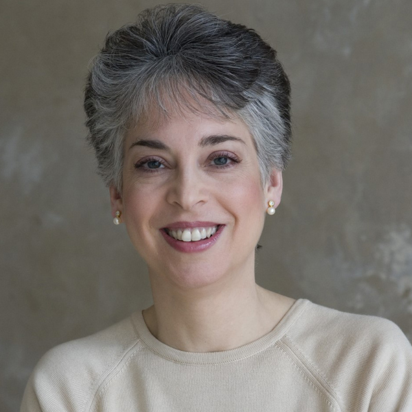 Woman smiling wearing a cream colored sweater