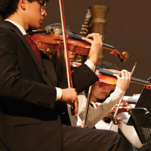 Teenager playing violin in an orchestra