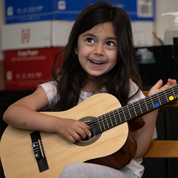 Young girl smiling and playing the guitar