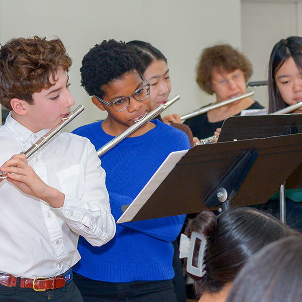 Mixed group of young students playing the flute