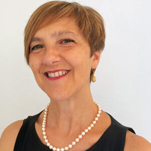 Woman smiling wearing a black top with white pearls