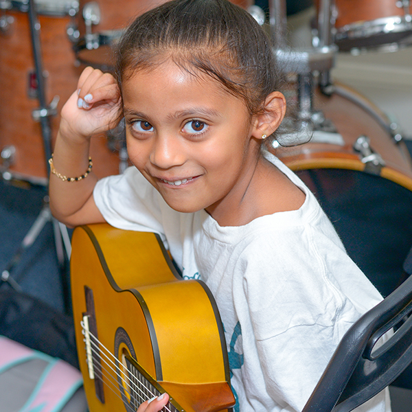 Young girl smiling holding a guitar