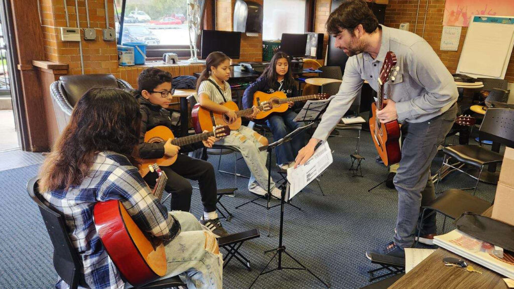 teenagers in a guitar class with their teacher