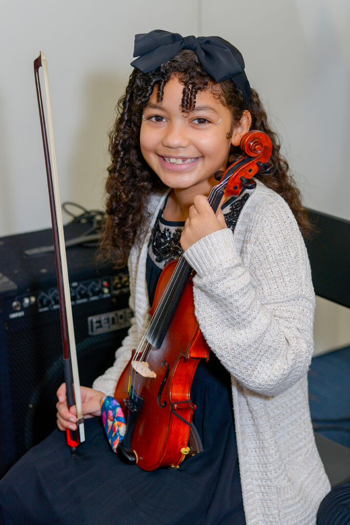 Young girl holding a violin and smiling