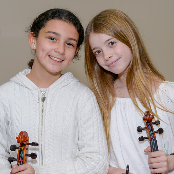 Two girls holding violins and smiling