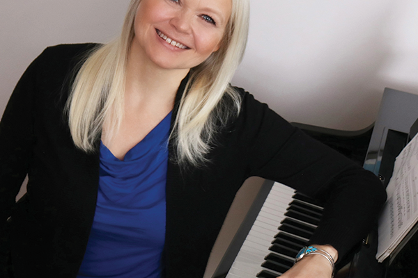 Kristin Halliday smiling seated at the piano