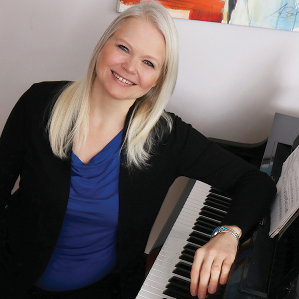 Kristin Halliday smiling seated at the piano