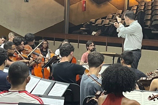 Man in white shirt conducting a youth orchestra