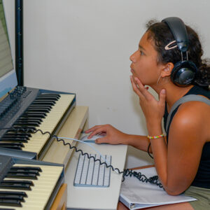 Girl with headphones at a computer and music keyboard