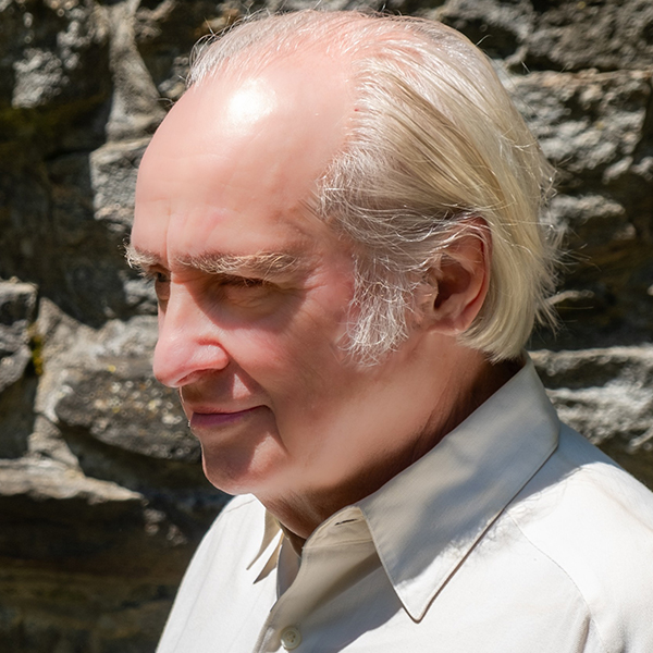 White balding man with white hair and grey shirt