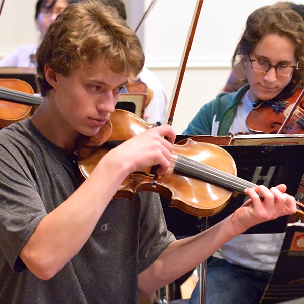 Young teens playing violins in orchestra