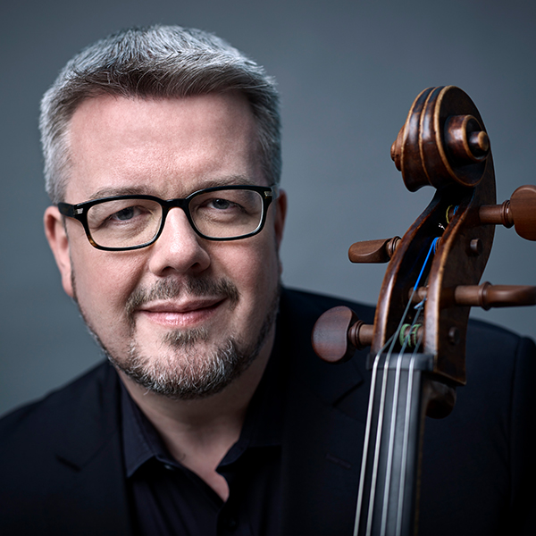 man with grey hair, glasses, go-tee, holding a cello