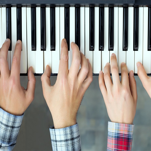 four hands playing the piano