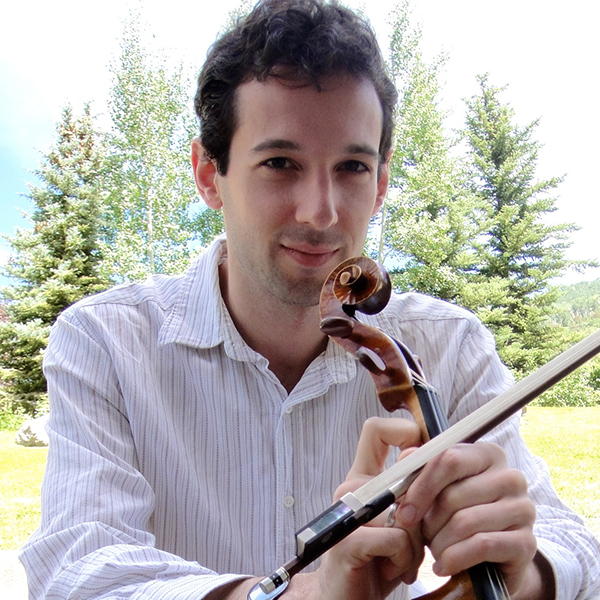 Man with dark hair posing with a viola in front of trees