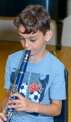 Young boy in blue shirt playing the oboe