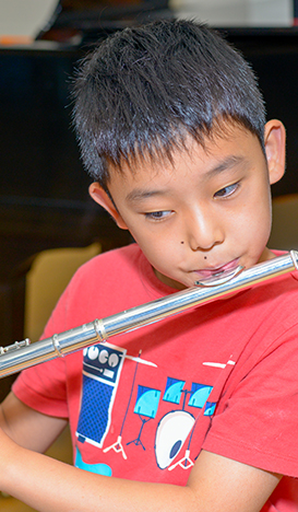 Young boy in red shirt playing the flute