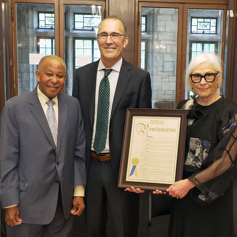 Two men and one woman holding a proclamation