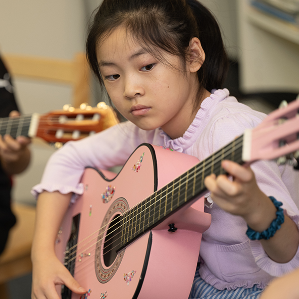 Young Asian girl playing a pink guitar