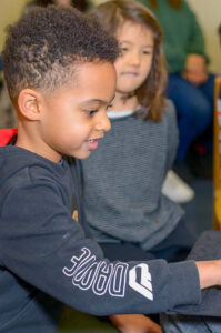 Young boy playing the piano while a young girl watches
