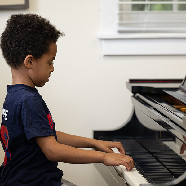 Young boy in blue shirt playing piano