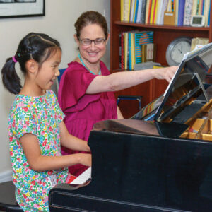 Young girl smiling while taking a piano lesson