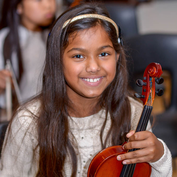 Girl holding a violin and smiling