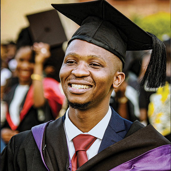 Young man smiling in cap and gown